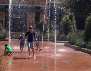 Kids play in the geysers Friday afternoon at The Shops at Highland Village.
