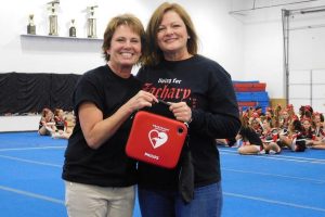 Karen Schrah from Living 4 Zachary presented Julie Hutchens, owner of Excite Cheer & Gymnastics, an Automated External Defibullator (AED) for the gym.