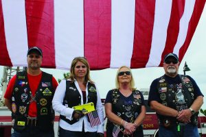 Old Glory serves as the background for Patriot Guard Riders (from l. to rt.) Brian Adams and Amy Weber of Lewisville and Sue and Howard Griffths of Flower Mound. The Patriot Guard motorcycle riders attend the funerals of fallen service members at the families’ requests. Photo by Dru Murray.