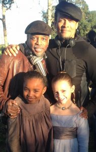 Kiera Strauss, bottom right, as the young Missy with Saniyya Sidney in the role of Kissy are pictured with Executive Producer Levar Burton, who performed the role of Kunta Kinte in the original version of "Roots" in 1977, and Director Mario Van Pebbles, top right.