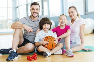 Happy to be a family. Happy sporty family bonding to each other while sitting on exercise mat together