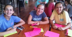 Avree Whittle, Libbie Foster, and Ashlyn Lamont write cards to refugees overseas.