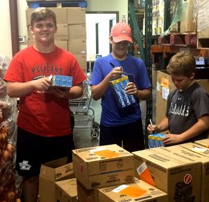Harlan Haire, Truett Walker, and Cameron Jeffers price items for CCA’s food pantry.