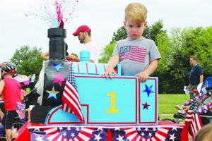 Oliver Breeden, 2, of Flower Mound, is serious about being the engineer of his Fourth of July Thomas the Tank engine his grandfather Keith Johnson constructed for him. “It was repurposed for the parade,” said Oliver’s mother Aimee. Photo by Dru Murray.