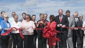 Denton County Commissioner Bobbie Mitchell holds the red ribbon as local and state officials, engineers and project heads of the 35Express Project give it a snip to signify the opening of the new bridge over Lewisville Lake. County Judge Mary Horn wields the big scissors. (Photo by Christina Ulsh/Lewisville Texan Journal)